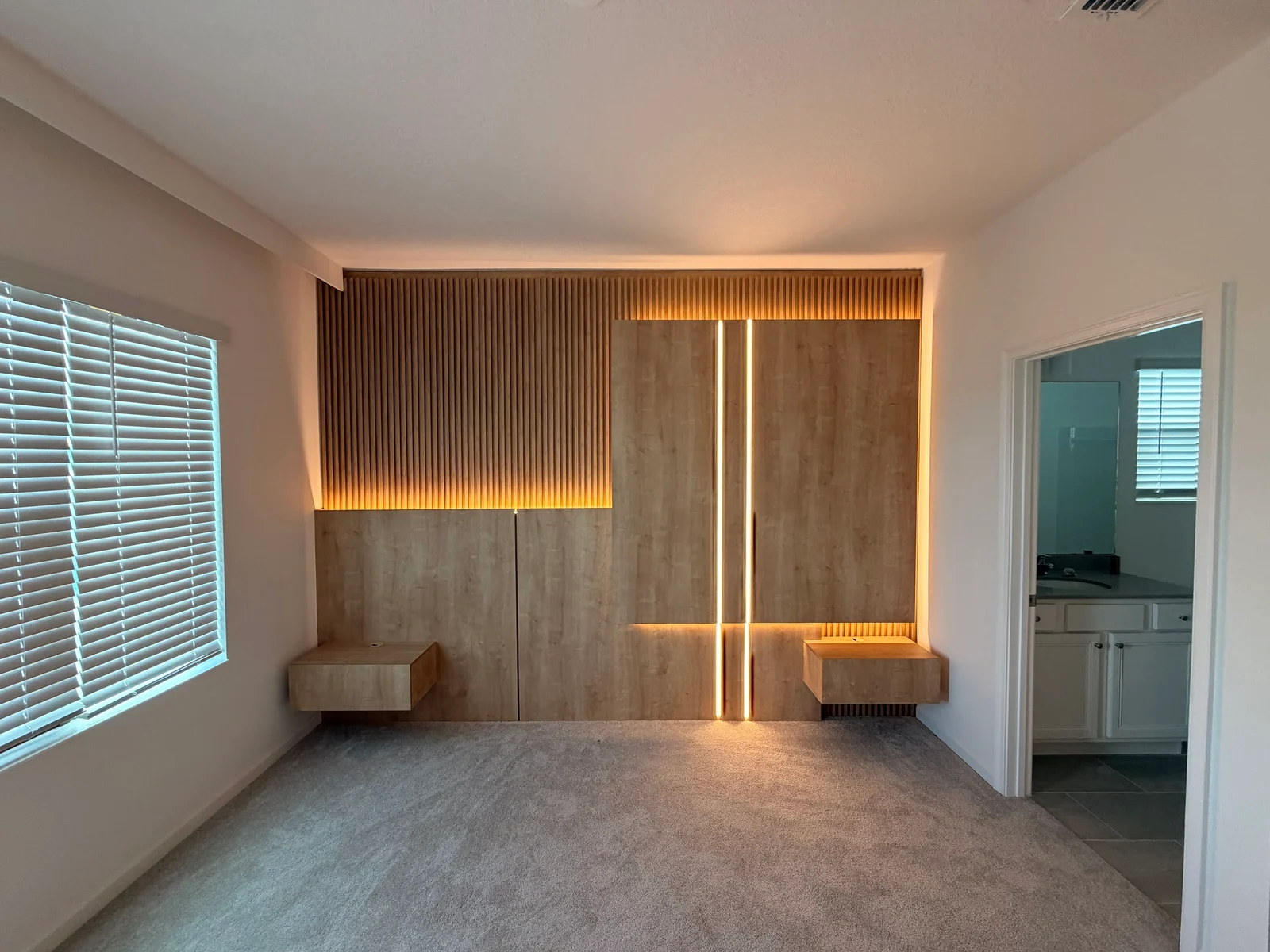 Slatted bedroom wall panel with a curved center, lighting and floating bedside cabinets.