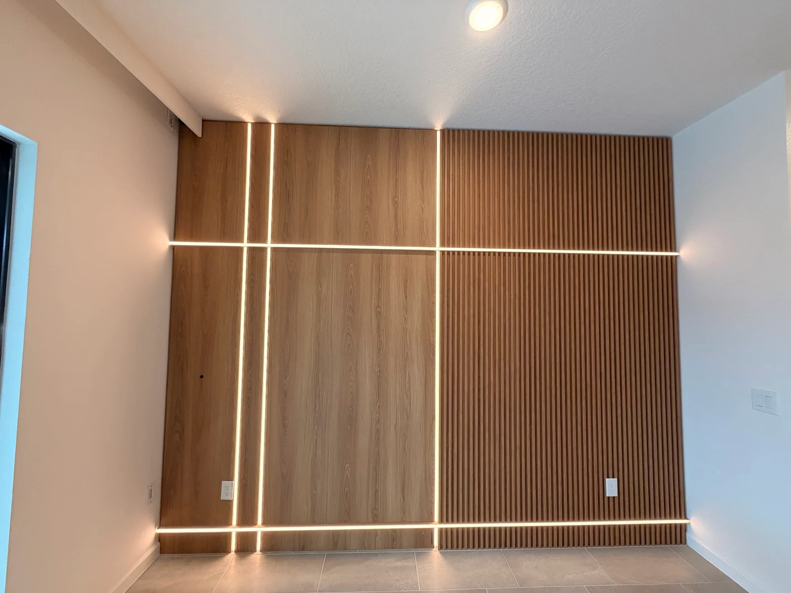 Bedroom storage wall fitted around a window with upper cabinets, slats and floating bedside cabinets.